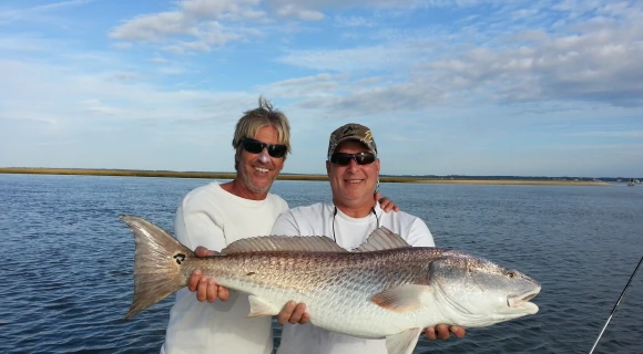 Two men holding a large fish on a boat