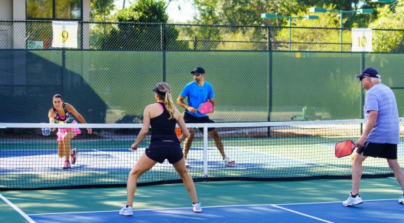 Four people playing pickleball outside