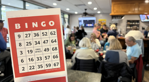 red bingo card in the forefront with restaurant guests at Big Jim's in the background