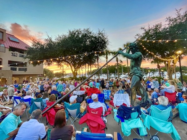 crowd watches live music under the statue lights at sunset at Shelter Cove