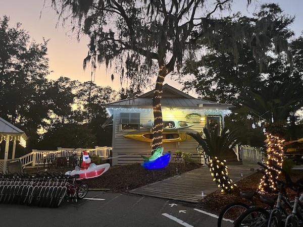 exterior of the Hilton Head Outfitters store with holiday lights and a Santa inflatable with the sunset in the background