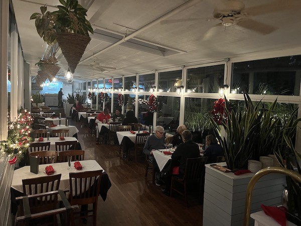 dining tables in Alexander's sunroom with red holiday decorations and lights