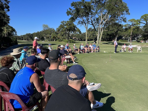 many observers watching male golfer putt on the greens at Palmetto Dunes Golf Academy
