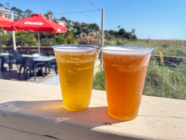 two draft beers on the railing of the Dunes House deck with the dunes in the background