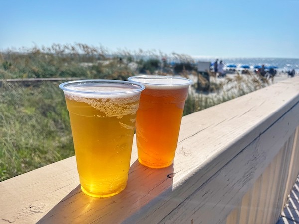 two beers on the railing of the Dunes House with the ocean in the background