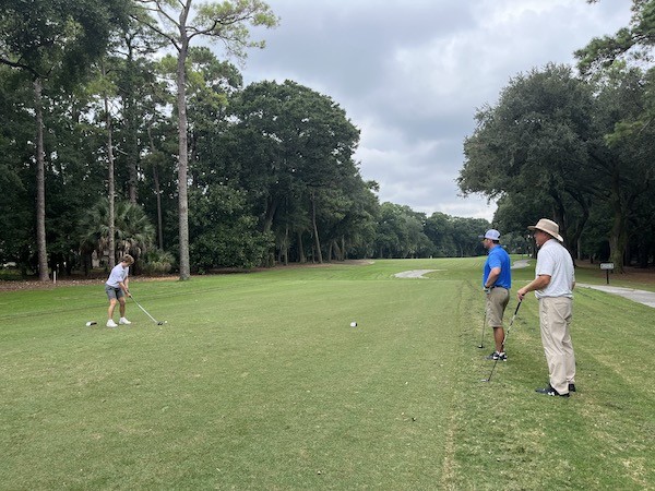 son practicing his drive during a lesson with father and Doug Weaver looking on