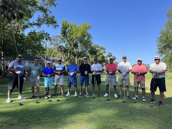 large group of golfers posing on the green with clubs