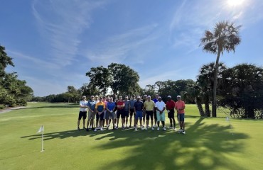 group of male golfers on the course surrounded by palm trees