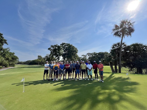 group of male golfers on the course surrounded by palm trees