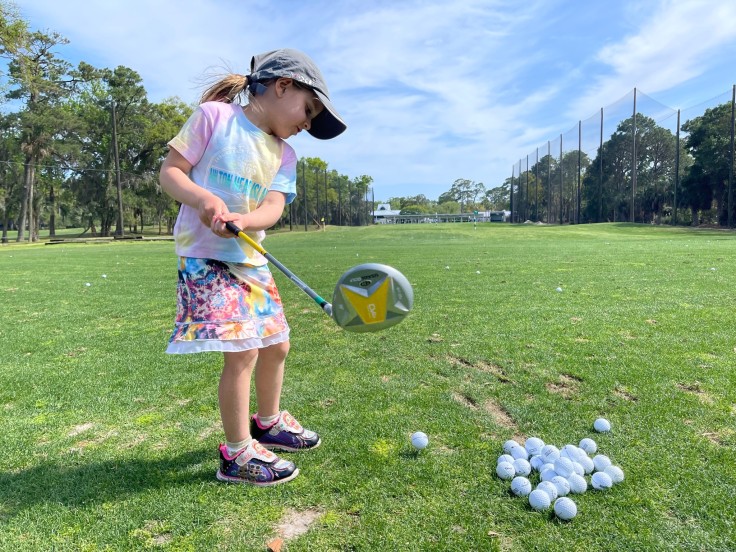 little girl mid golf swing at the driving range at Palmetto Dunes Golf