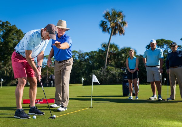 Doug Weaver giving putting lessons to male golfer while students observe on the side at the Palmetto Dunes Golf Academy