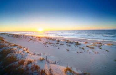 sunrise over the beach and dunes with a runner