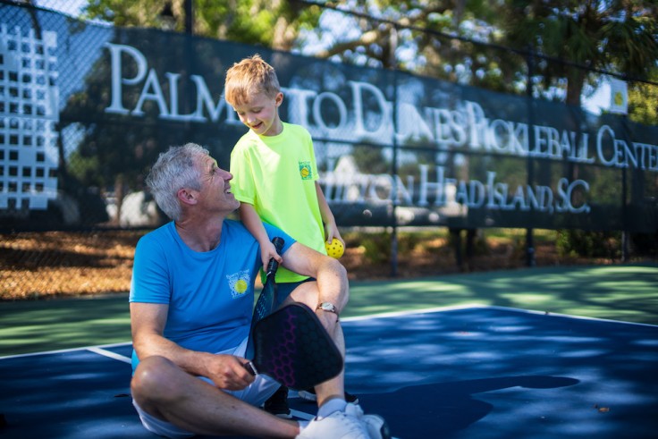 old man and young boy with pickleball paddles on the Palmetto Dunes Pickleball court