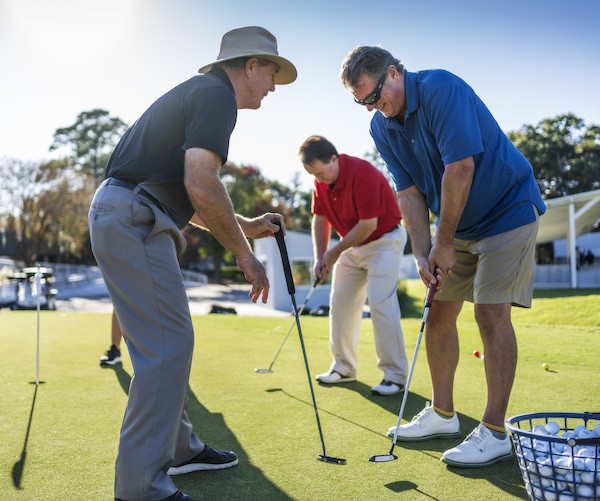 two male golfers practicing putting with Palmetto Dunes Golf Academy instructor Doug Weaver