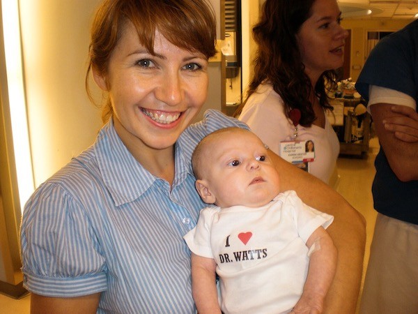 Dr. Yulia holding Baby Skylar wearing a onesie that says 