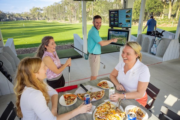 People laughing over food at the Toptracer Range located at the Robert Trent Jones Golf Course