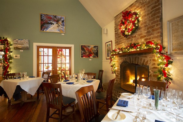 cozy fireplace with Christmas garland and wreath lit up with red ribbon inside Alexander's restaraunt