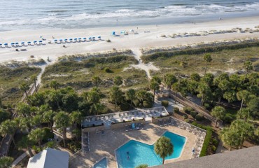 aerial view of resort pool and lounge chairs overlooking dunes and ocean at Captains Cove