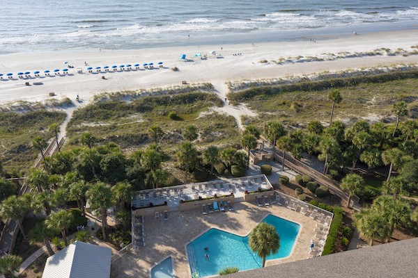 aerial view of resort pool and lounge chairs overlooking dunes and ocean at Captains Cove