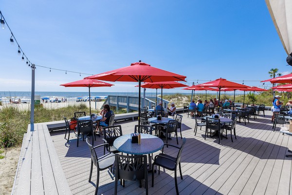 table and chairs with red umbrellas on the new deck of the Dunes House restaurant