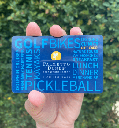 palmetto dunes gift card in hand against a greenery background
