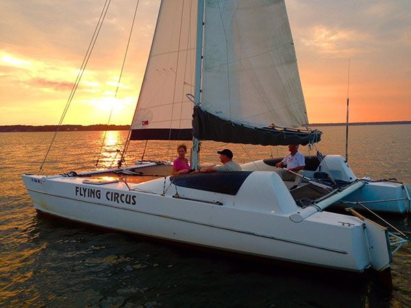 couple on a sailboat charter with sunset in the background