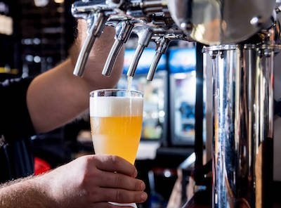 bartender pouring draft beer under tap