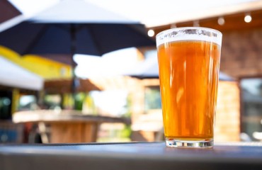 close up of amber beer with umbrella and table in background