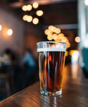 glass of beer with lights and bar in background