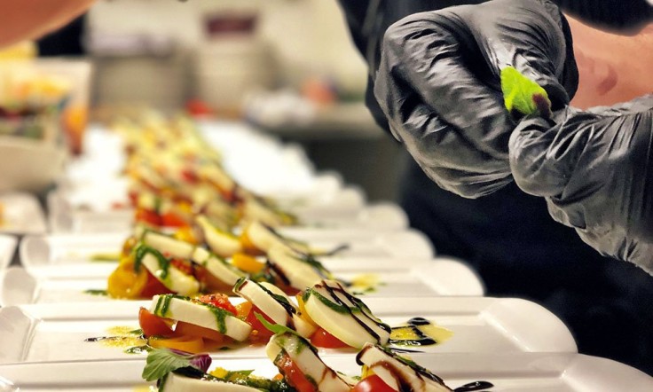 chef with black gloves putting together caprese salads