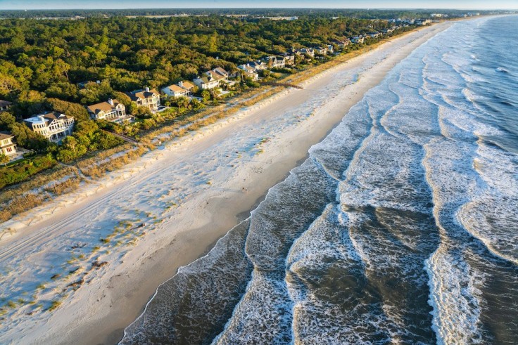 aerial view of ocean waves and beachfront houses in a row