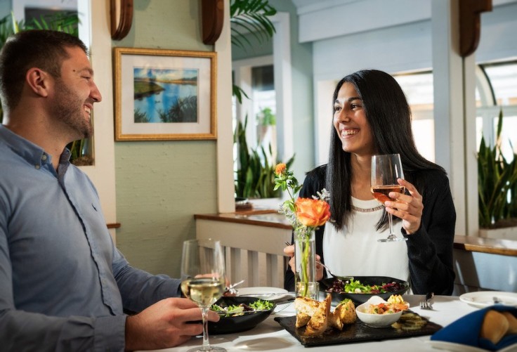 man and woman smiling laughing and drinking at dinner