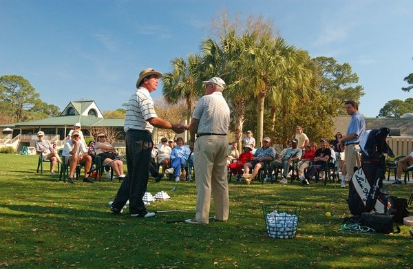 Doug Weaver shaking hands with golfer during golf demo with students in the back