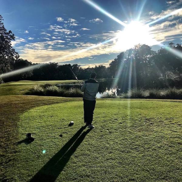 Golfer after his swing on the course with sun glare in the sky