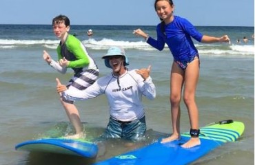 girl and boy on surf boards in ocean with surf instructor