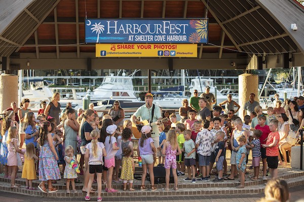 Shannon Tanner singing in front of a large group of kids under the HarbourFest pavillion