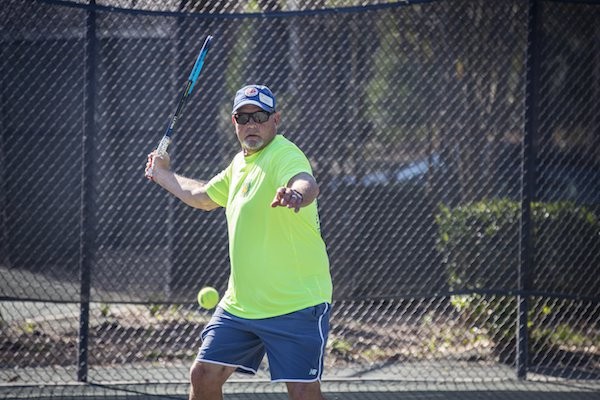 Eric swinging tennis racket during warm up