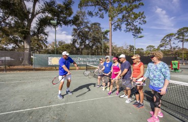 Palmetto Dunes Tennis Instructor teaching students a swing technique on the court