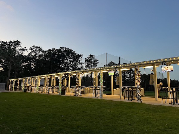 another angle of the empty Toptracer driving range bays at night with holiday lights along the roof and poles