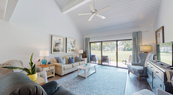 open living room with coastal decorations and sliding door to golf views