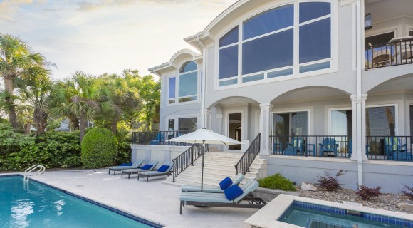 rear view of the Palmetto Dunes Oceanfront vacation home with large windows and pool