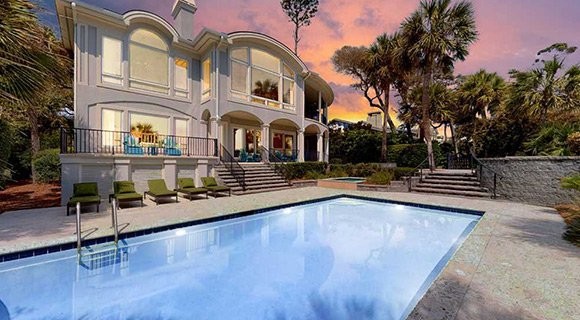 view of private pool and back of the house with gorgeous pink sunset surrounding the Palmetto Dunes Oceanfront vacation home