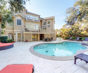 backyard of rental home with deck, lounge chairs, and pool