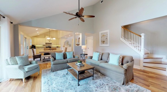 open plan living area of rental home with tan and blue couches and white kitchen in the background