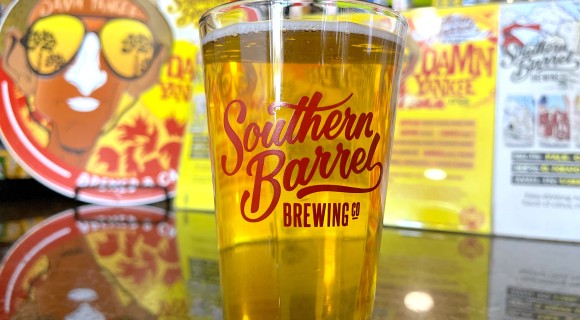 beer in a Southern Barrel Brewing pint glass on a table with signage blurred in the background