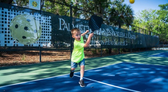 little boy hitting a pickleball on the Palmetto Dunes Pickleball Center court