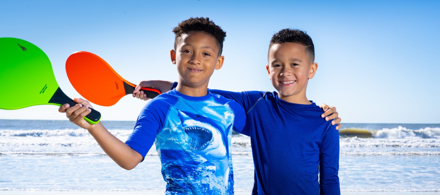 two young boys with rackets on the beach