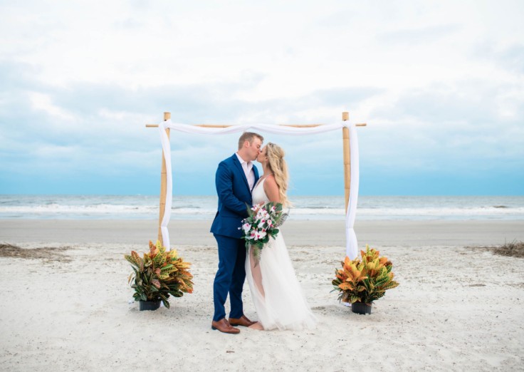 bride and groom kissing under the ceremony arbor on the Palmetto Dunes Beach