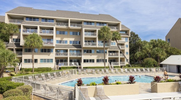 Captain's Walk community pool with seating surrounded by palm trees and buildings