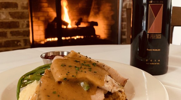 view of turkey and gravy, bottle of wine, and fire in background at Alexander's Hilton Head